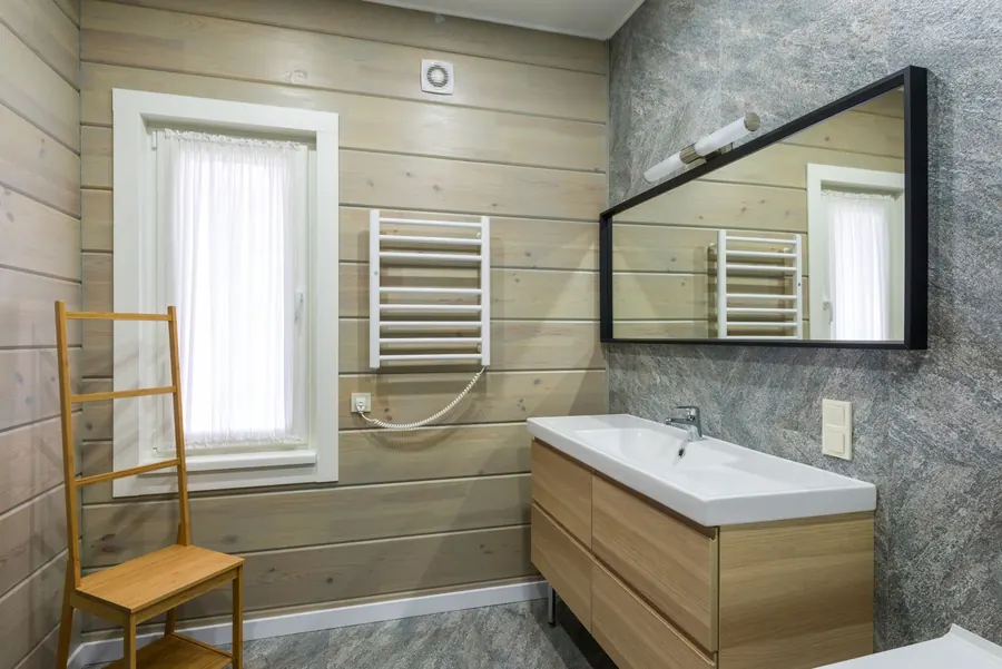 Bathroom with a wall-mounted extractor fan above a curtained window, next to a heated towel rail