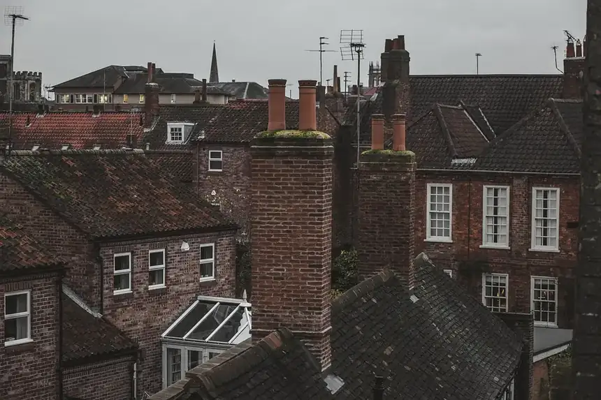Rooftops of red brick houses with clusters of chimney stacks and tiled roofs