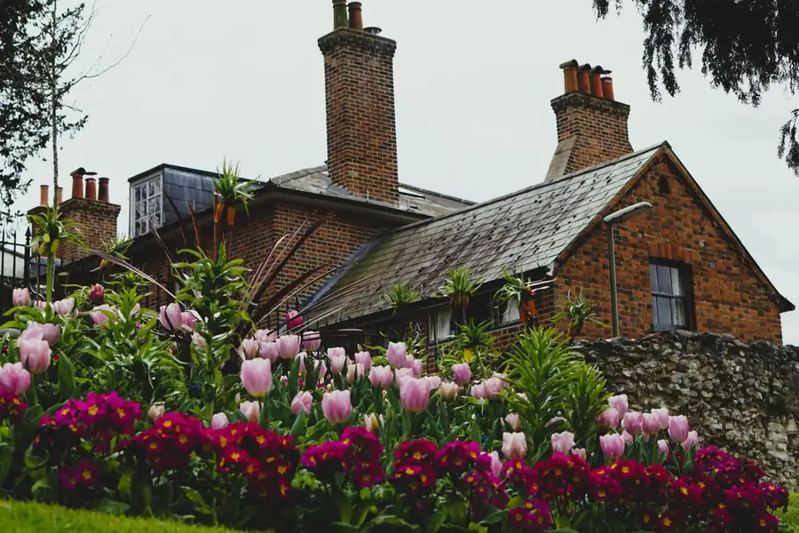 Tall brick chimney stacks topped with clay pots set in mortar flaunching on an older slate-roofed house