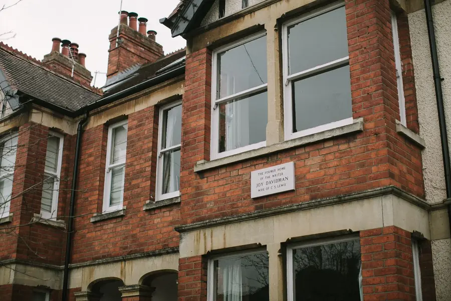 Edwardian red brick house with two chimney stacks carrying clay pots above a slate roof