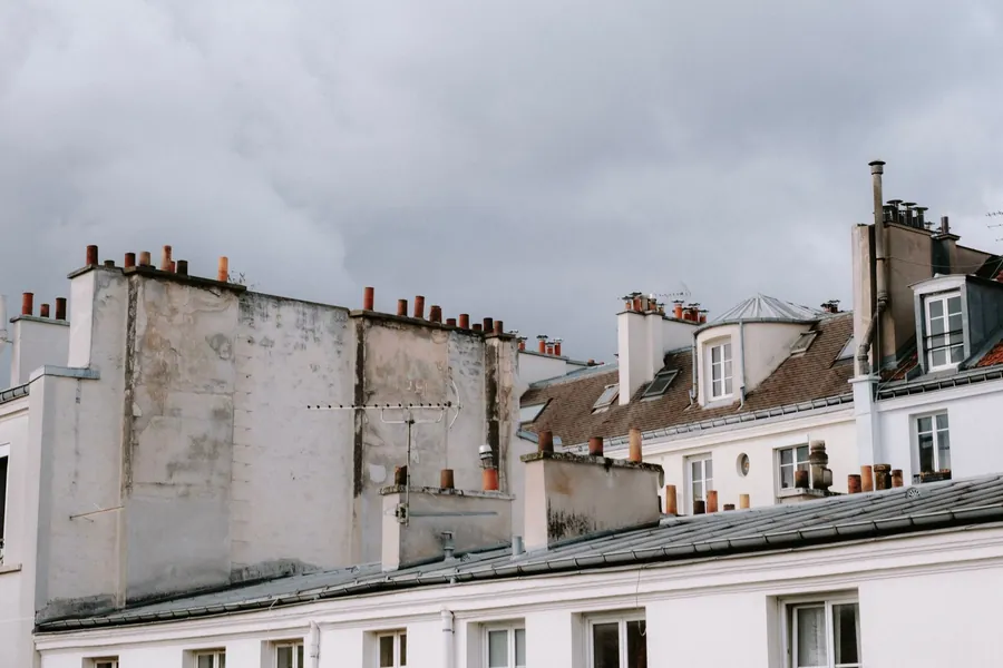 Terraced rooftops with brick party wall parapets and chimney stacks rising through the slopes, the abutments where flashing leaks start on Croydon terraces