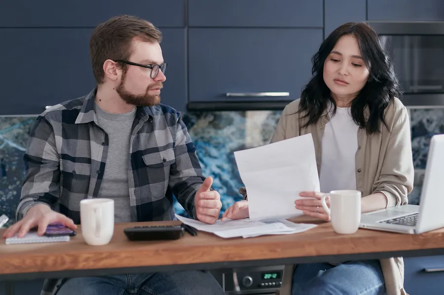 A couple at a kitchen table reading through a written repair quote together