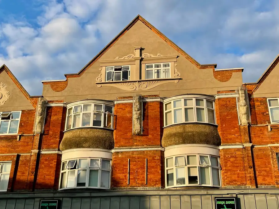 Red brick Edwardian building with projecting bay windows and a gabled roof, the kind of bay roof junction that leaks on older Croydon houses