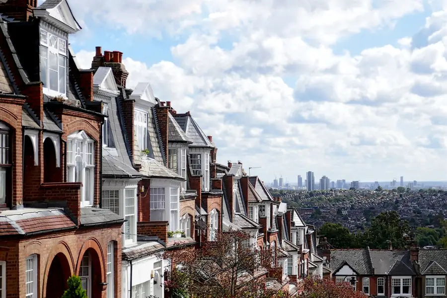 Row of red brick Edwardian houses on a hillside with a wide view across the London suburbs behind
