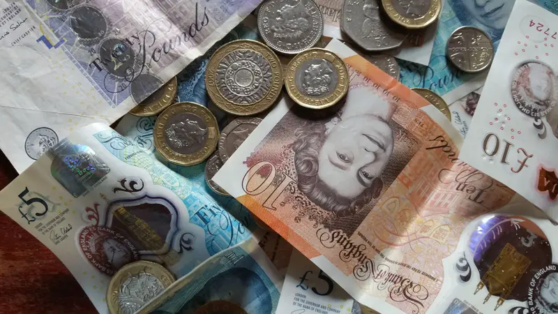 Pound notes and coins representing the cost of an emergency roof callout in Croydon