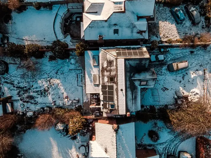 Overhead view of a suburban house in snow with a flat roofed rear addition and rooflights beside its pitched main roof