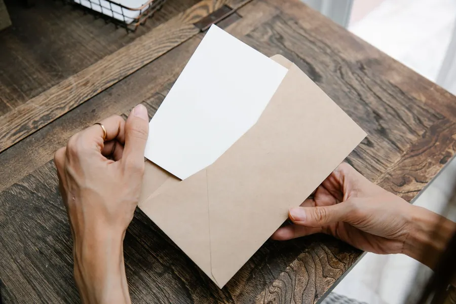 Hands opening a brown envelope containing a letter, like a party wall notice delivered to a Croydon neighbour