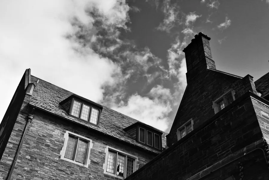 Slate roof slope meeting a taller brick wall at an abutment, the junction that fails on back addition roofs