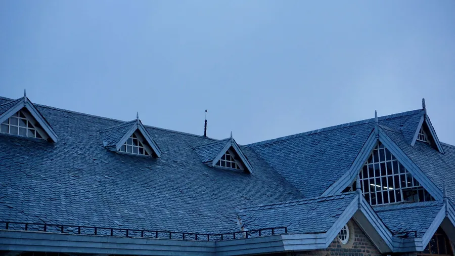 Grey slate roof with several dormers, each one creating a pair of valleys where the slopes meet