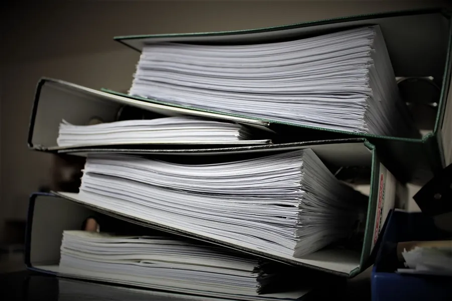 Stack of lever arch binders packed with paper documents