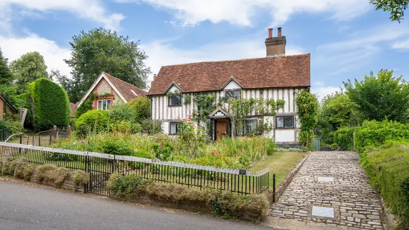 Period English house with a steep clay plain tile roof, a tall brick chimney and a gabled cross wing