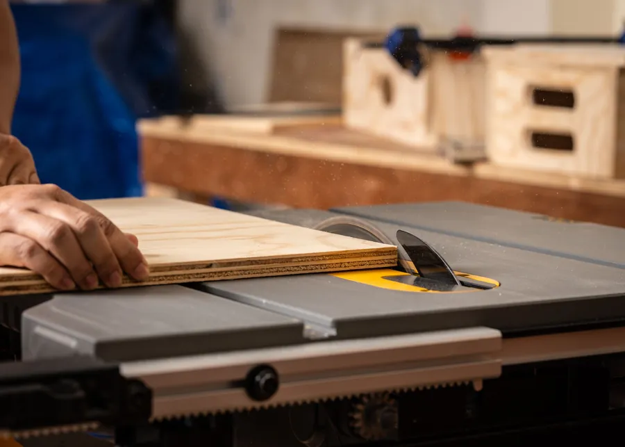 A sheet of layered timber board being cut on a saw bench, the kind of decking material laid over flat roof joists