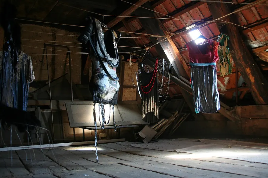 Old unfelted roof space with daylight showing through the tiles and washing hung to dry from the rafters