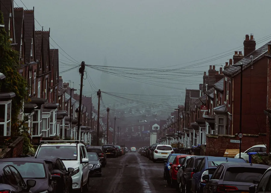 Long street of Victorian terraced houses with chimney stacks on a wet, overcast day