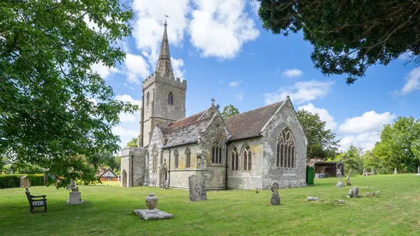Medieval stone parish church with a spire and a churchyard lawn