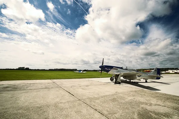 Vintage propeller fighter aircraft parked on an airfield under a big sky