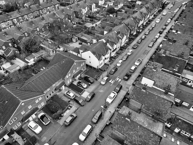 Black and white aerial view of a long suburban road lined with detached and semi-detached houses
