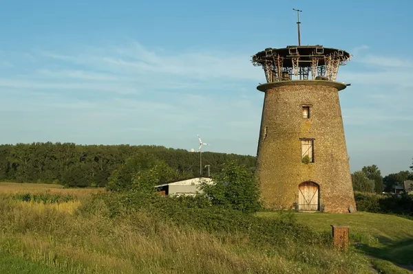 Old tower windmill without its sails standing in open grassland