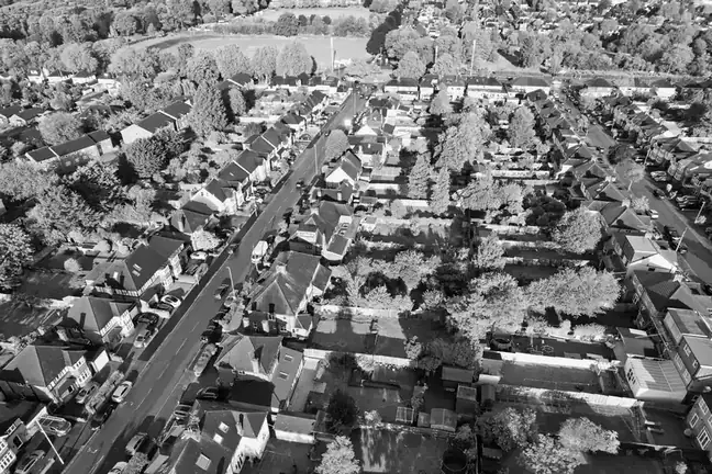 Black and white aerial view of suburban streets and house roofs among trees