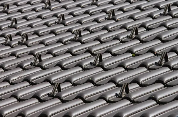 New dark grey interlocking roof tiles laid in even courses on a replacement roof