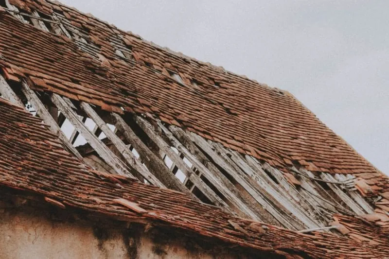 A clay plain tile roof with whole courses of tiles missing and the battens showing, the kind of damage that needs pricing in Croydon