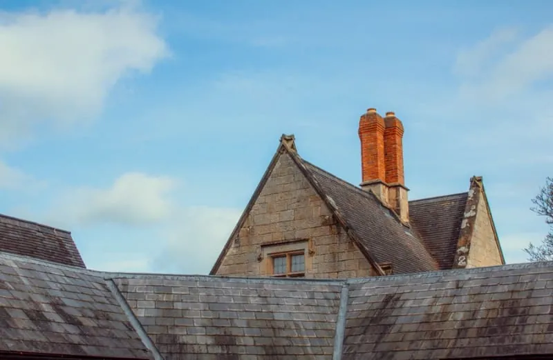 Brick chimney stack rising from a slate roof with lead-lined valleys where the lower roof slopes meet, the junctions that leak most on Croydon houses